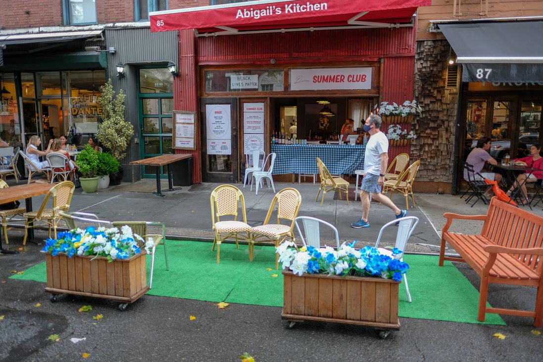 fake grass in a parking spot with tables set up for outdoor dining